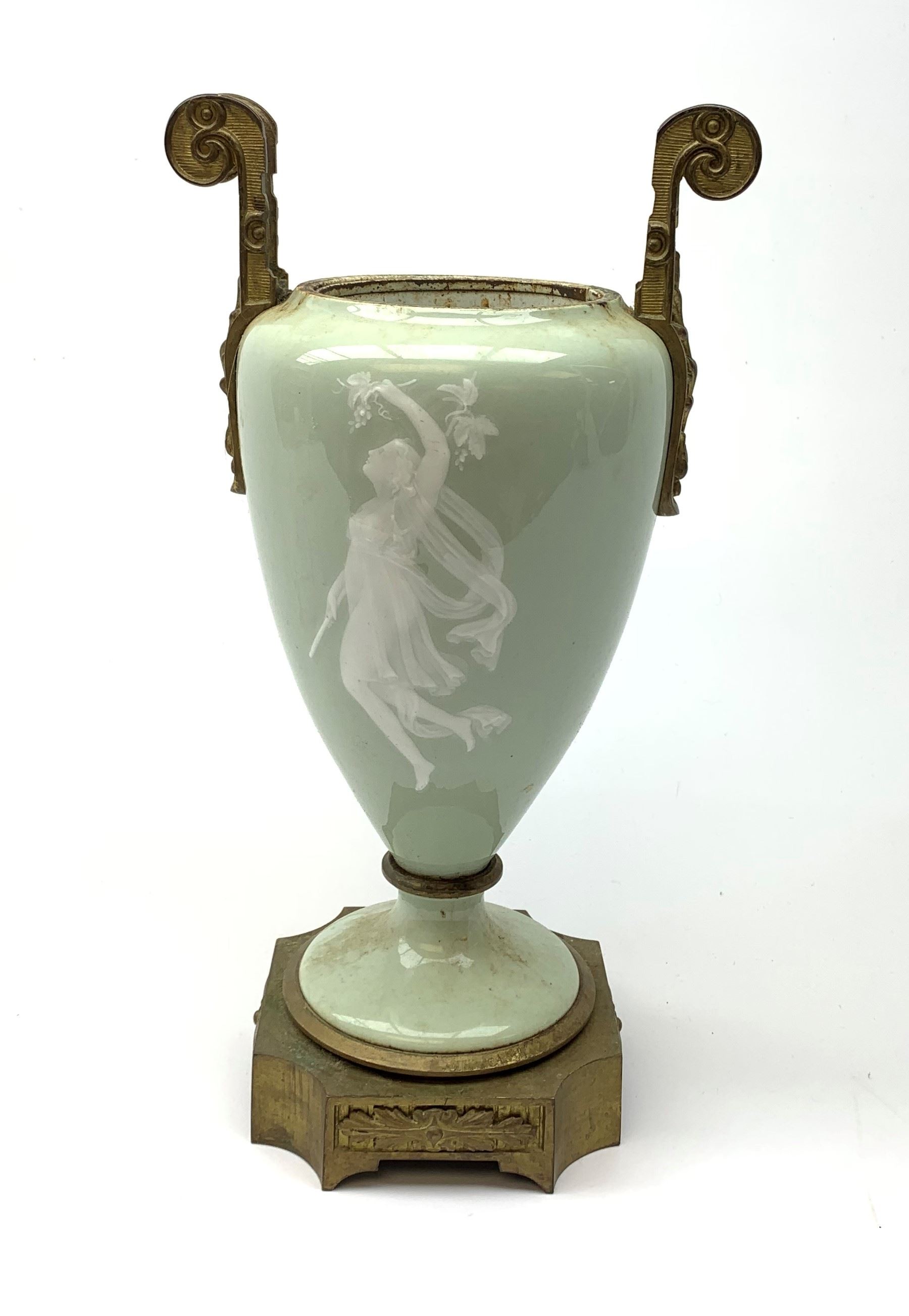 A pate sur pate celadon green vase, of baluster form decorated with a classical female figure to one side, and floral swag with ribbon and musical trophy to the other, with twin gilded scroll handles, and raised upon a gilded base, overall H38.5cm. 