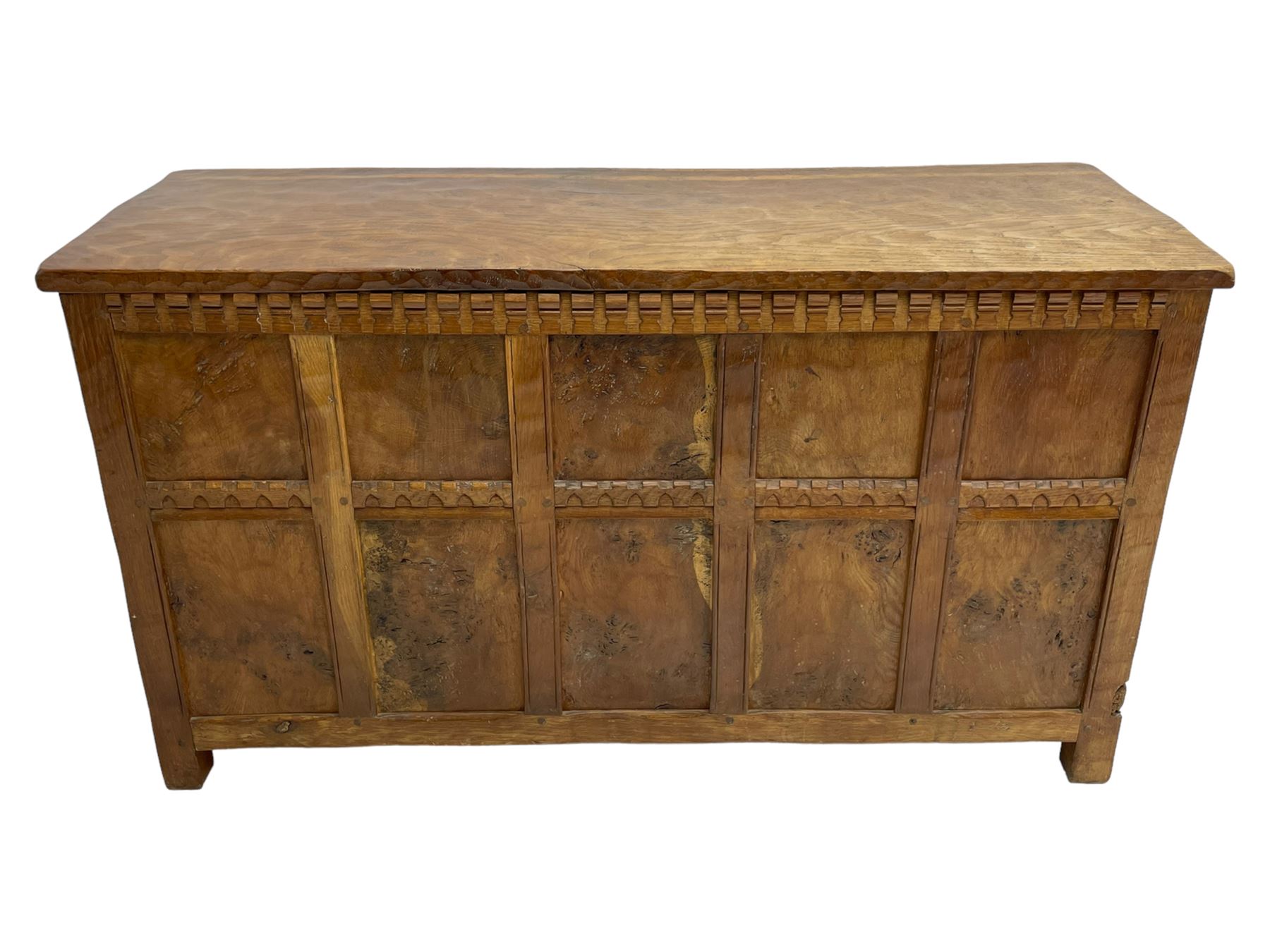 Gnomeman - oak blanket box, all-over adzing, the hinged top over figured and burr panelled front, decorated with carved crenellations and arcade, carved with gnome signature, pierced handles to each end forming the central rail, wrought metal hinges, on stile supports, by Tom Whittaker, Littlebeck, Whitby