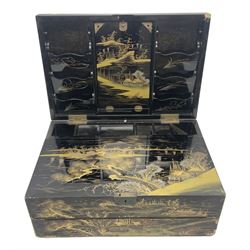 Early 20th century Japanese lacquered writing box, the hinged lid decorated with village scene with Mount Fuji in the distance opening to reveal compartmented interior with folding writing slope, with twin handles, W47cm H20cm D32cm