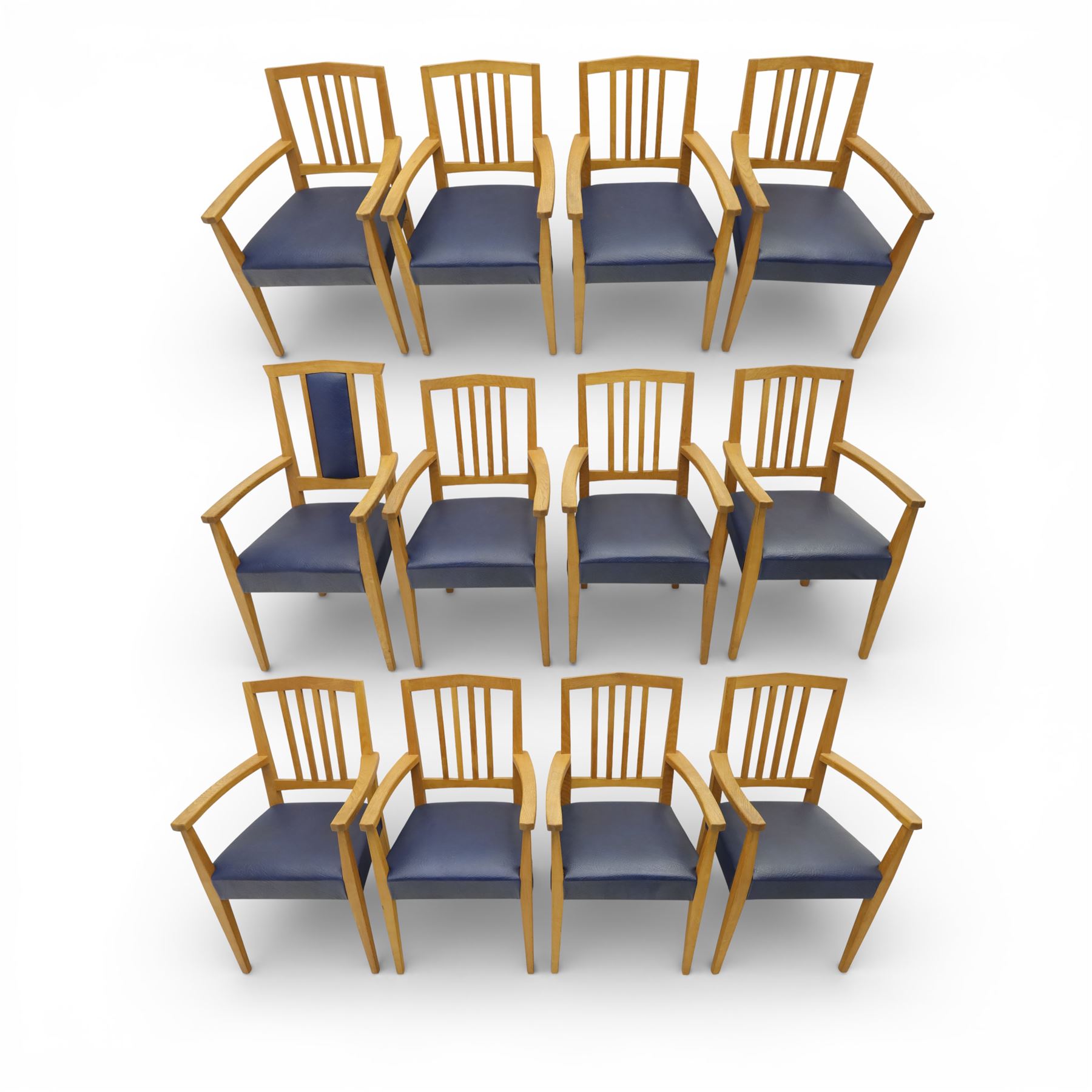 Modern twelve oak dining chairs including one 'Chairmans' chair, solid oak construction, slatted back and arm rests, blue leatherette padded seat, on tapered square supports 