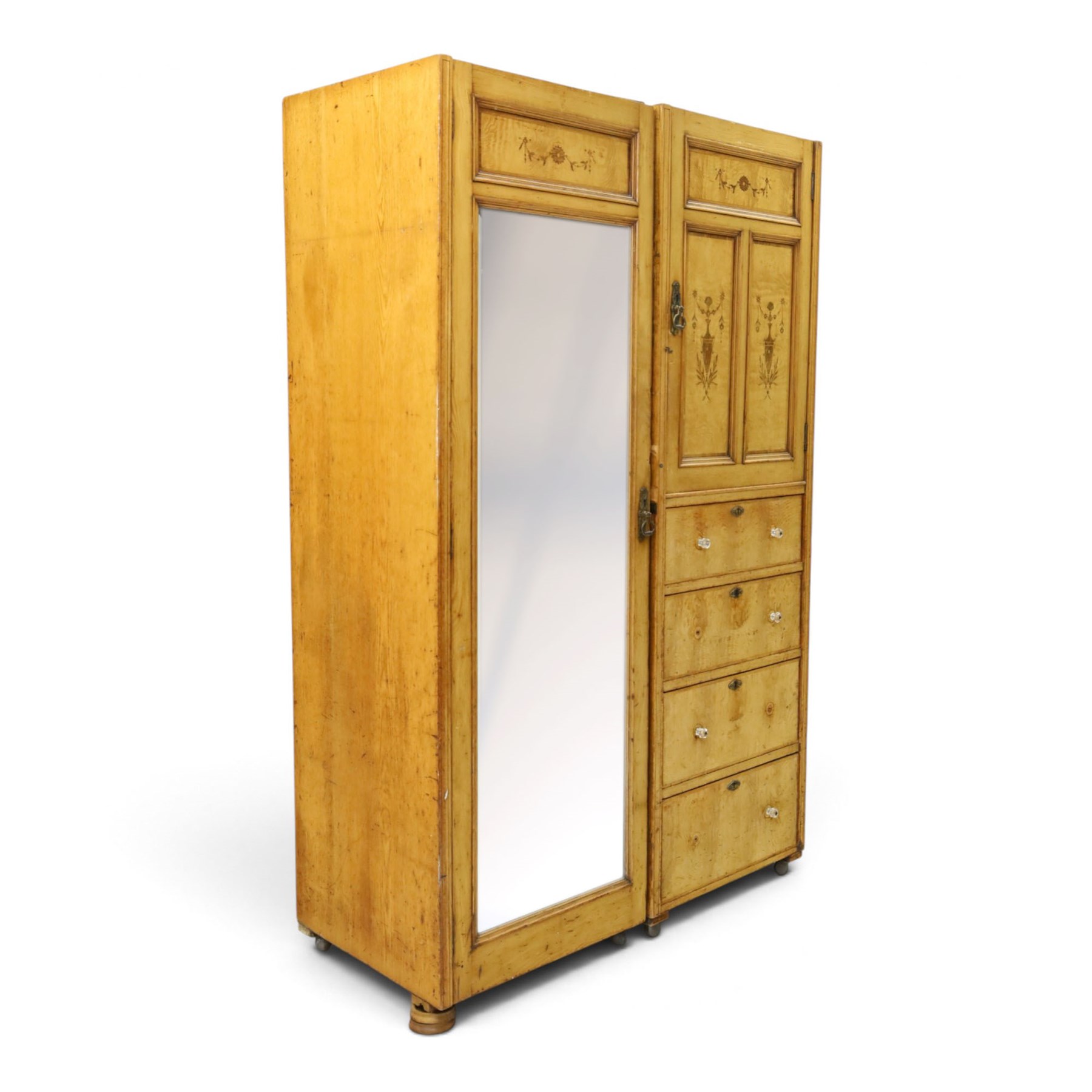Edwardian Neoclassical figured ash and inlaid double combination wardrobe, the left section with mirrored door enclosing a hanging rail, the right section with cupboard door above four graduated drawers with glass knobs, raised on castors