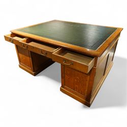 Late 19th century twin pedestal oak partner's desk, rectangular top with inset green leather writing surface, fitted with nine graduating drawers to each side, the rear drawers enclosed by panelled cupboards
