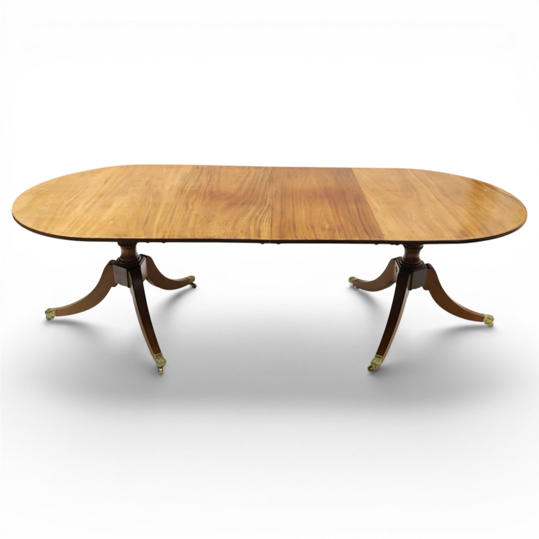 Acornman - mahogany twin pillar extending dining table, strongly grained top with inlaid edge, raised on a ring turned baluster column, above three swept supports terminating in brass paw feet above castors, two additional leaves extending the table to 242cm, with signature carved acorn, by the workshop of Alan Grainger of Brandsby