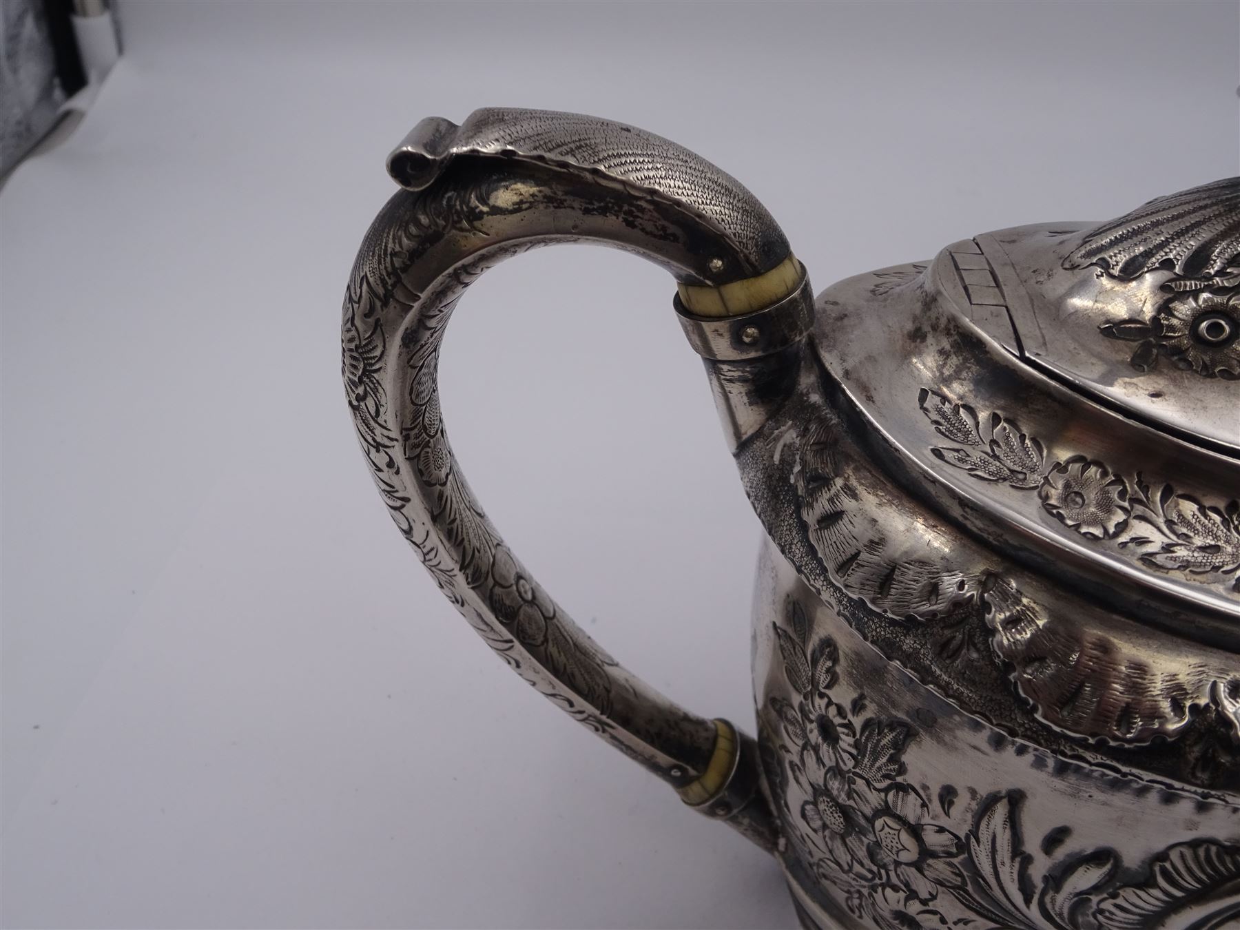 George III silver teapot, of oval form, with embossed foliate, floral and scroll decoration and engraved central cartouche, with acanthus capped C handle with ivory insulators, hallmarked John Emes, London 1807 This item has been registered for sale under Section 10 of the APHA Ivory Act
