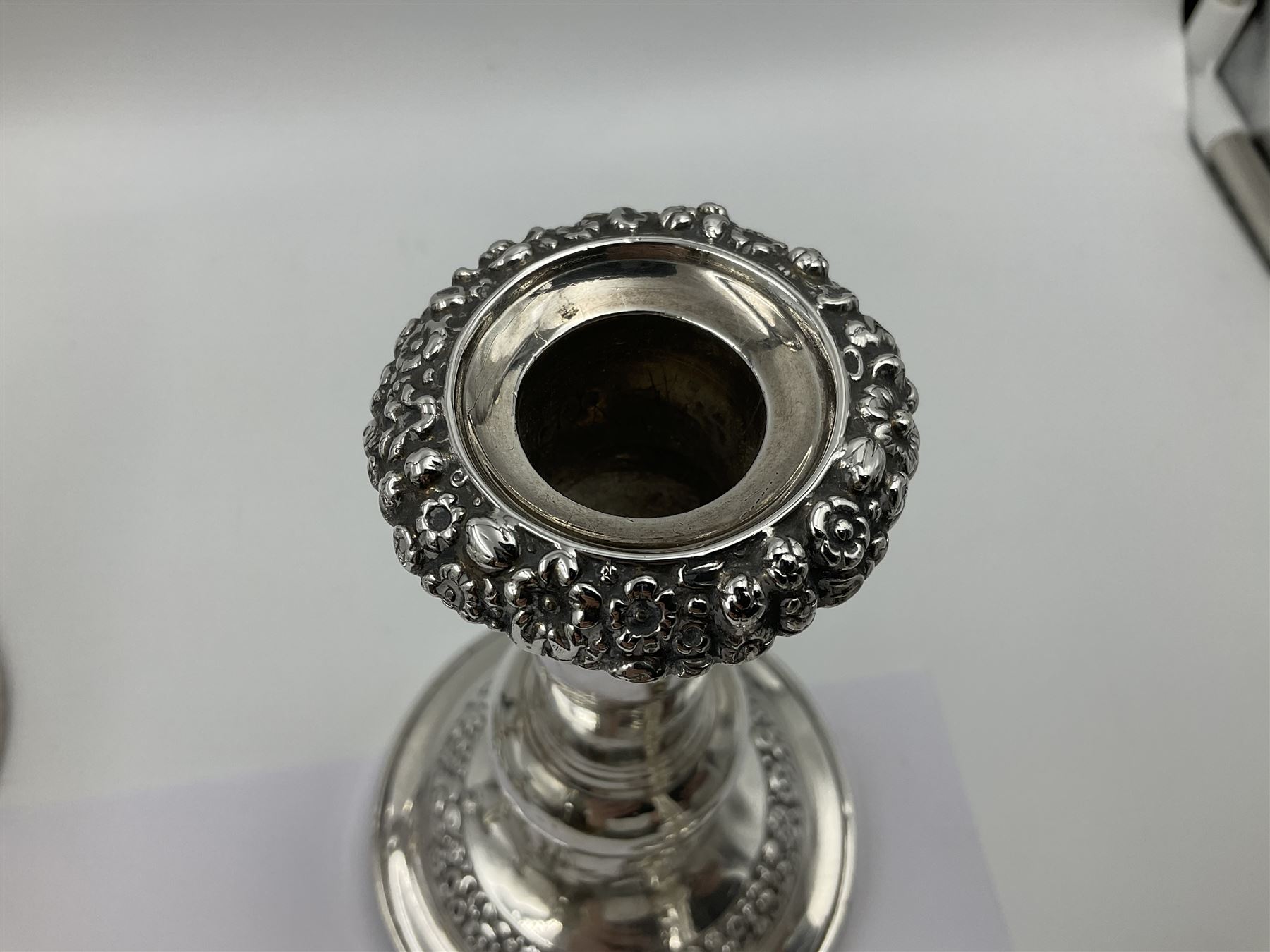 Four George III silver candlesticks, each upon knopped stem and weighted circular stepped foot, the foot and removable sconce repousse decorated with a band of flower heads, hallmarked to sconce and foot Thomas & John Settle, Sheffield 1820, H17.5cm