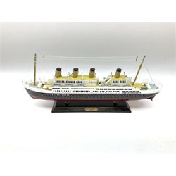Wooden model of RMS Titanic, on a fixed black stand bearing plaque inscribed 'Titanic 1912', L54cm, H22cm, together with model of a sloop, gaff rigged on stand bearing plaque inscribed 'Sloop' L32cm, H42cm; and model of a fishing trawler on a stand bearing plaque inscribed 'Chalutier' L35cm, H28cm (3)