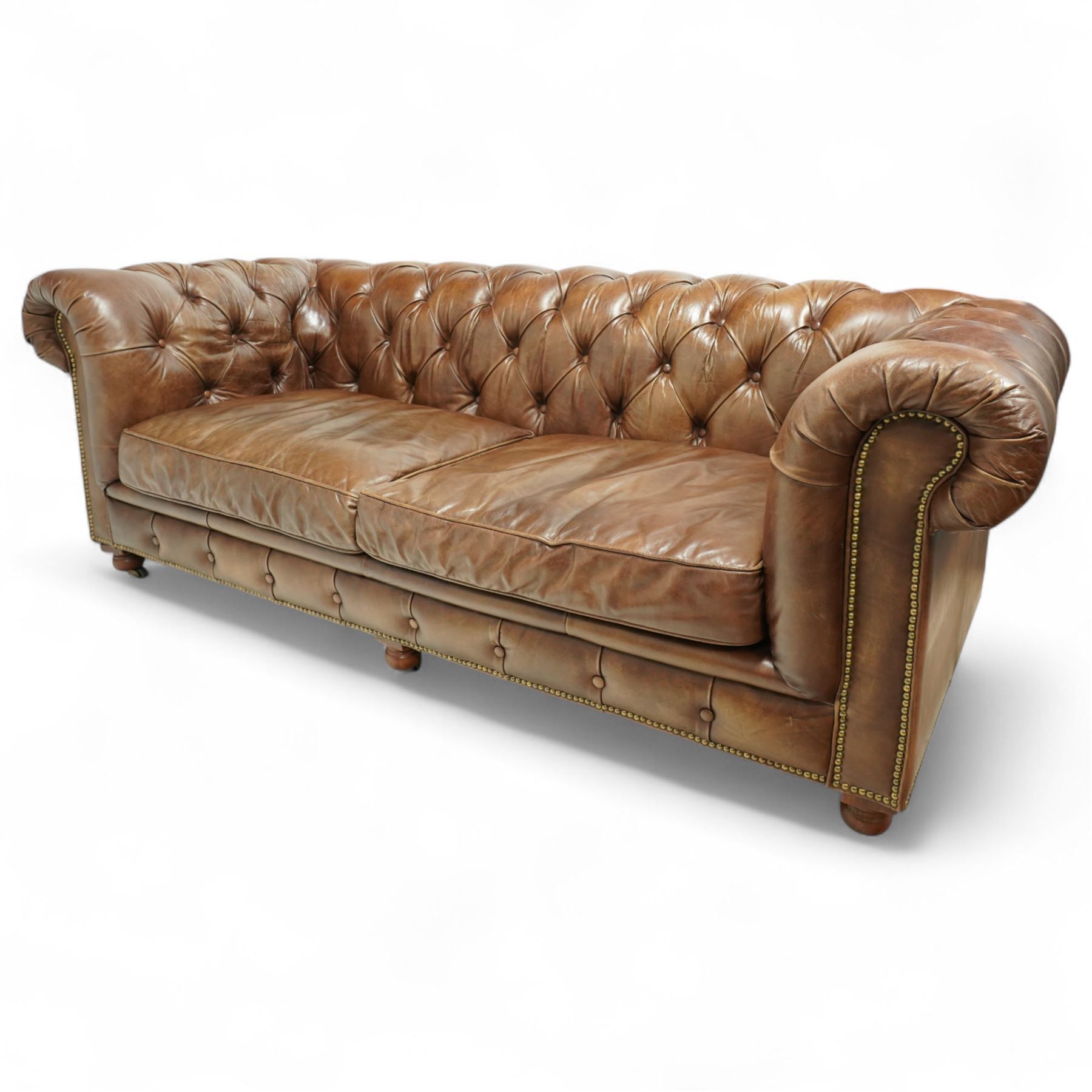 Timothy Oulton, Halo - late 20th century brown leather Chesterfield settee, the upholstered frame with deep buttoning to back and arms, large scroll terminals with brass studwork, twin seat cushions, raised on castored legs