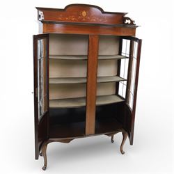 Edwardian mahogany display cabinet, arched back with satinwood and harewood marquetry foliate decoration above a moulded cornice, serpentine front fitted with twin glazed doors with astragal bars, the lower door panels inlaid with oval reserves, standing on elegant cabriole legs terminating in pad feet