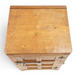 Mouseman - early-to-mid-20th century adzed and panelled dark oak bedside cupboard, raised back over rectangular canted top, fitted with single panelled cupboard door with chamfered rails and wrought iron fittings, enclosing two adjustable shelves, raised on canted square feet, carved with mouse signature, by the workshop of Robert Thompson of Kilburn