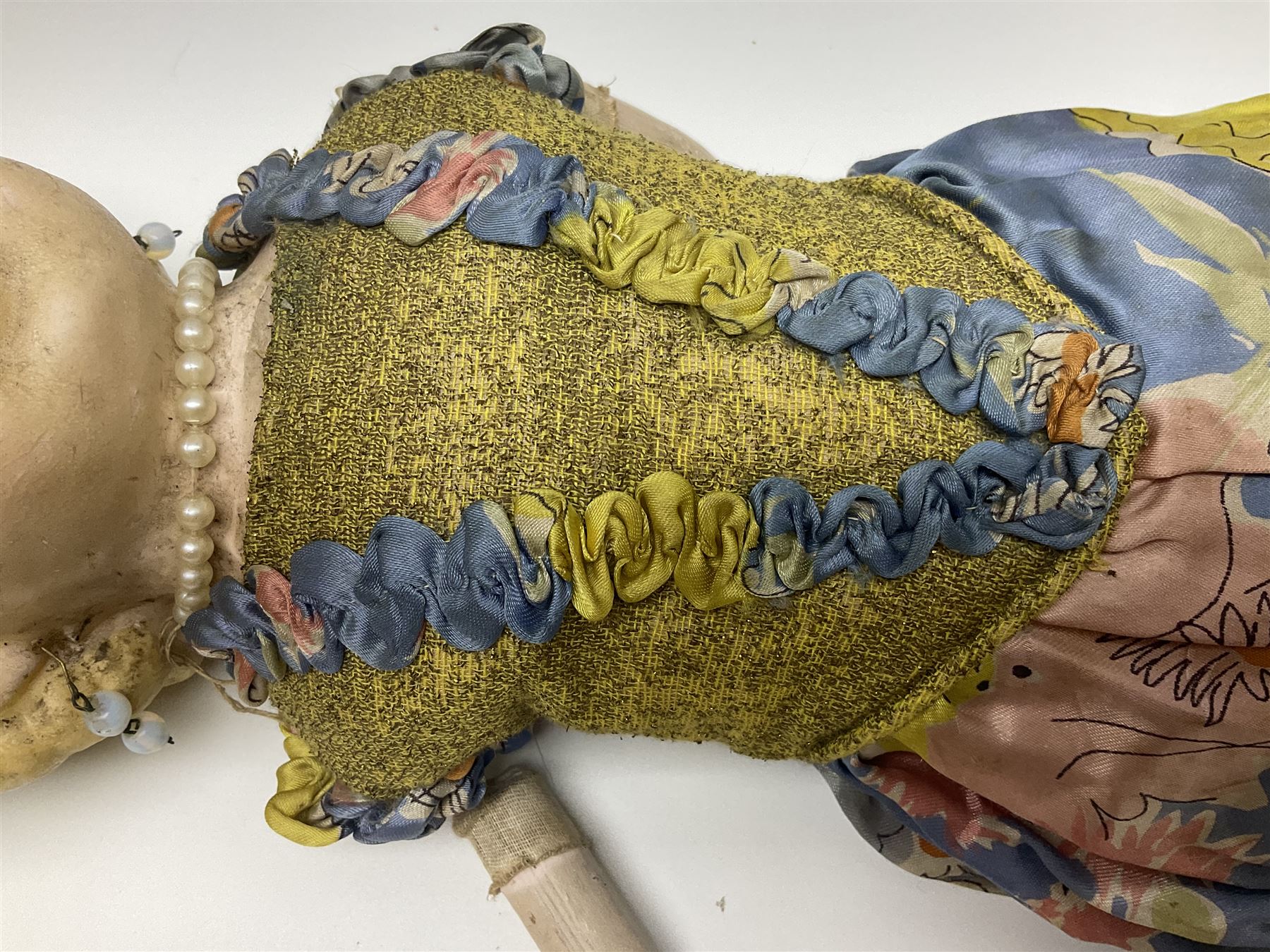 Victorian large wax over composition Pumpkin head doll, with inset dark glass eyes, moulded blonde hair in curls, stuffed body with carved and painted wooden limbs, grey painted boots, floral satin dress with netting underclothes H61cm