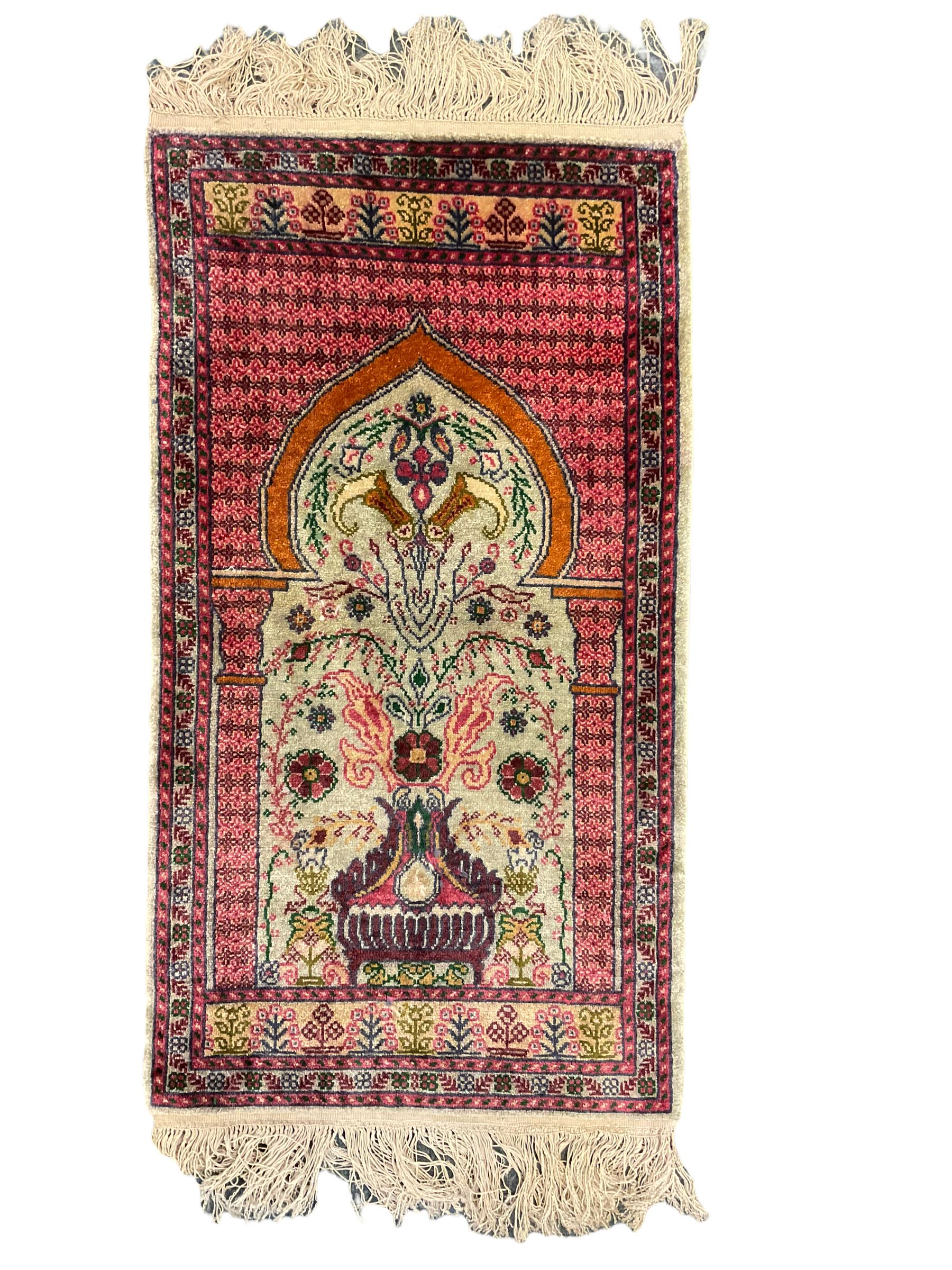Small Persian magenta ground rug, central Mirab with flanking columns enclosing stylised urn motif with trailing foliage, the triple band border with plant motifs (86cm x 46cm); Persian red ground rug, two central floral medallions with extending flower heads, floral decorated border (106cm x 53cm) (2)