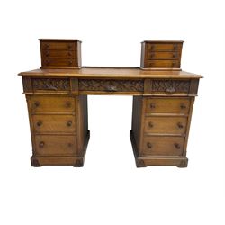 Late 19th century heavily carved oak twin pedestal desk, rectangular top with two raised trinket or correspondence structures each with three drawers, rectangular top over three frieze drawers carved with acorn and oak leaf decoration, each pedestal with three drawers with acorn husk shaped handles