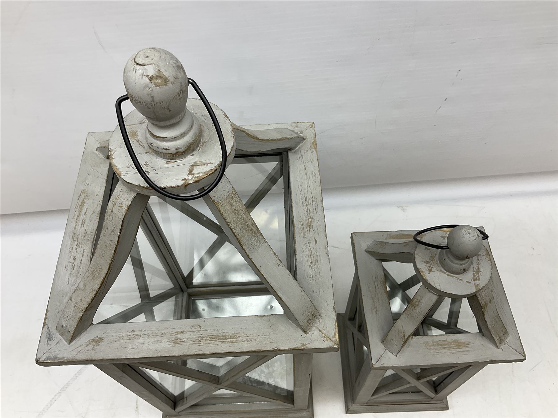 Two wooden lanterns with four glass sides, loop handles and open tops, largest example 58cm