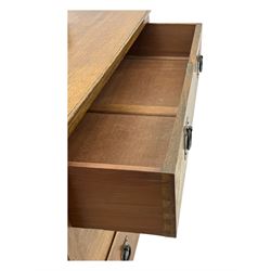 Early 20th century Arts and Crafts oak dressing chest, the arched mirror flanked by floral marquetry inlaid uprights above a shelf and drawer, over three long drawers with square hammered metal plates and circular pulls, on slender supports with castors