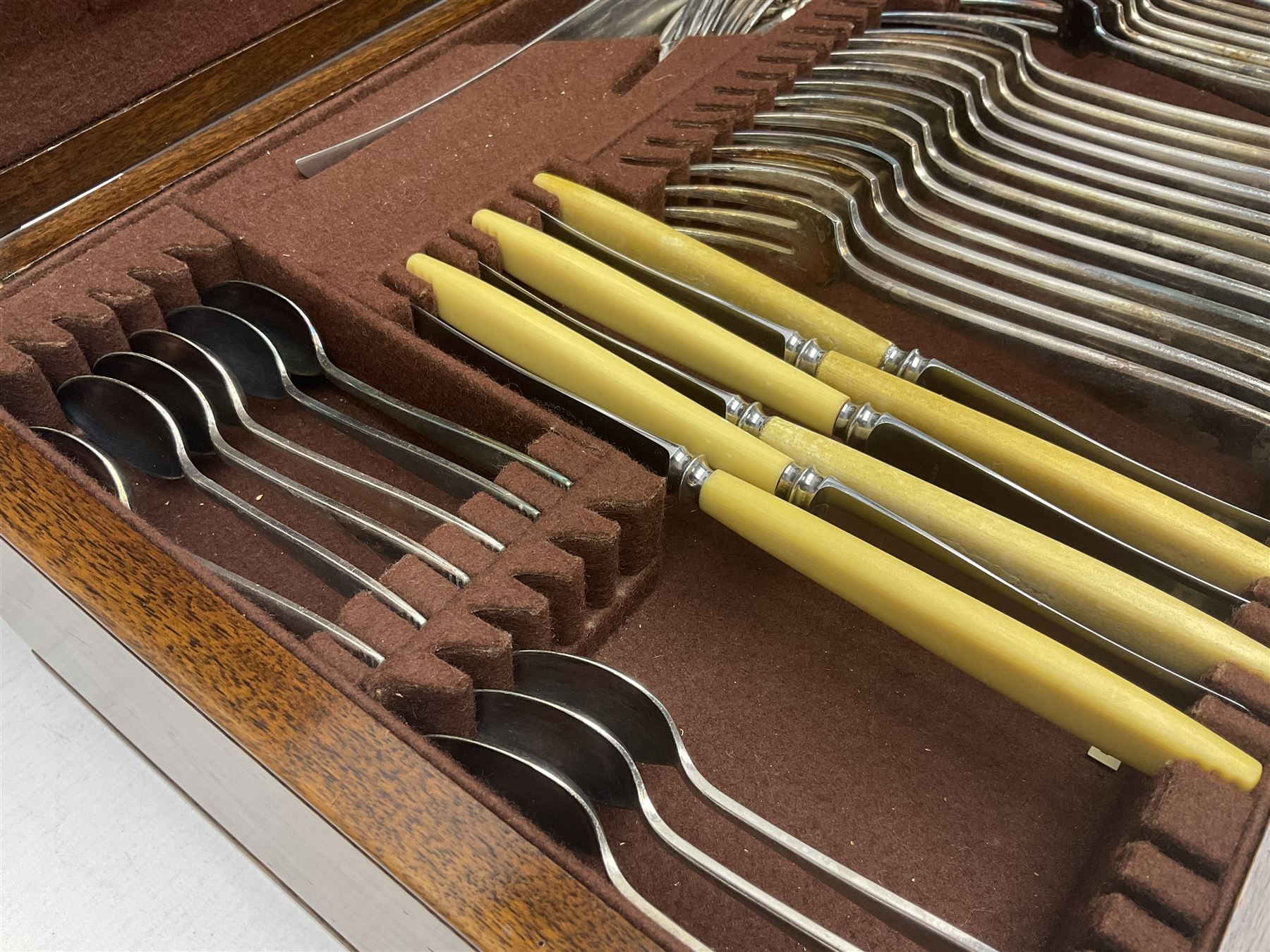 Elkington & Co part canteen of silver plated and stainless steel cutlery, to include simulated ivory handled examples, housed in oak and mahogany case, lock plate stamped 'Acme, British Made', W49cm D31cm H18cm