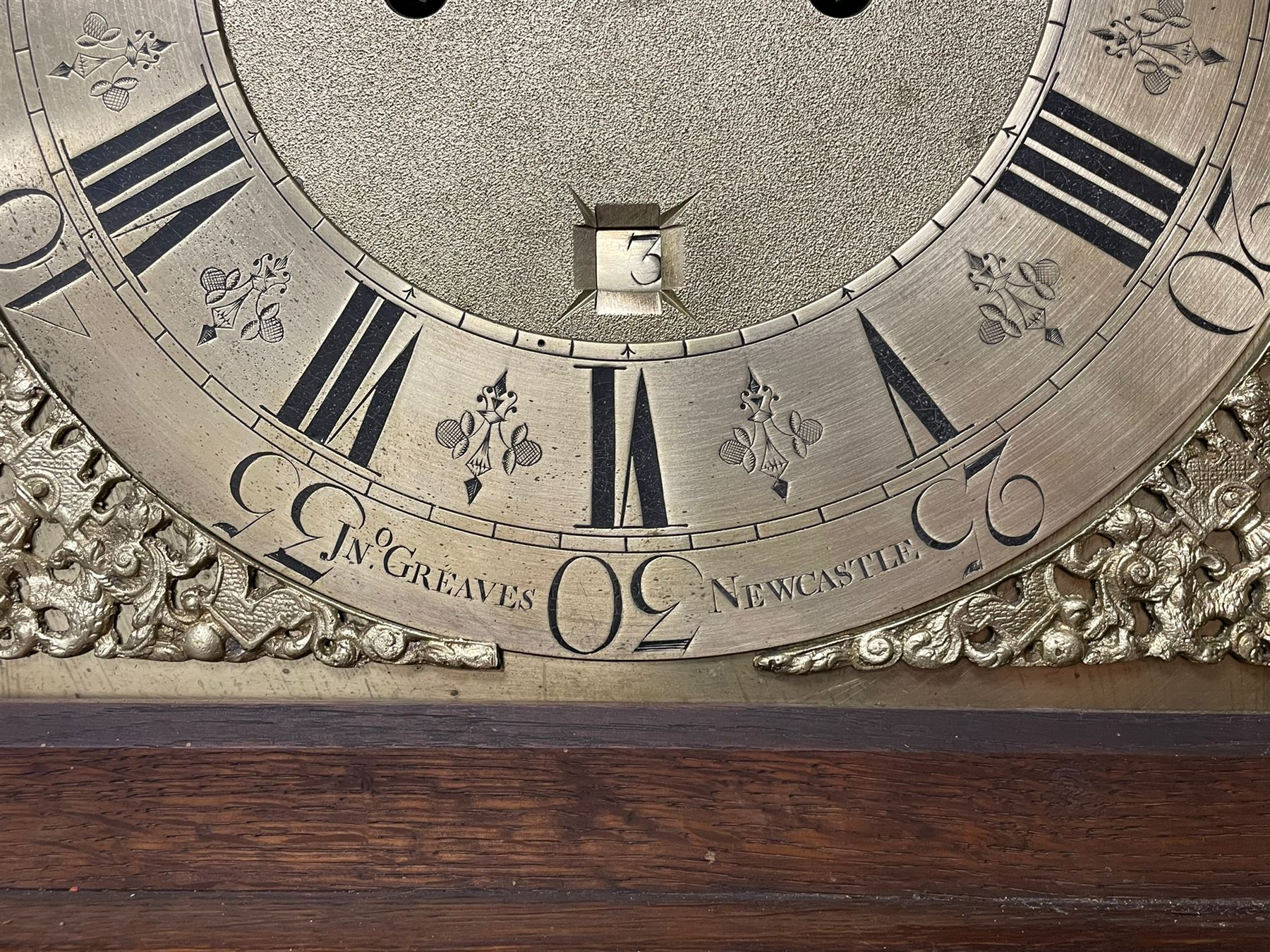 John Greaves of Newcastle - Mid-18th century 8-day oak longcase clock with a flat top, double cornice and break arch hood door flanked by two turned pilasters, trunk with canted corners and a spire topped door with crossbanding, rectangular plinth raised on bracket feet, brass dial with cast spandrels and penny-moon dial and pointer to the arch, matted dial centre with a silvered chapter ring and seconds ring, chapter with Roman numerals, five minute Arabic's, minute and quarter tracks, square date aperture and fettled steel hands, dial pinned to a rack striking movement with a recoil anchor escapement. With pendulum and weights.
