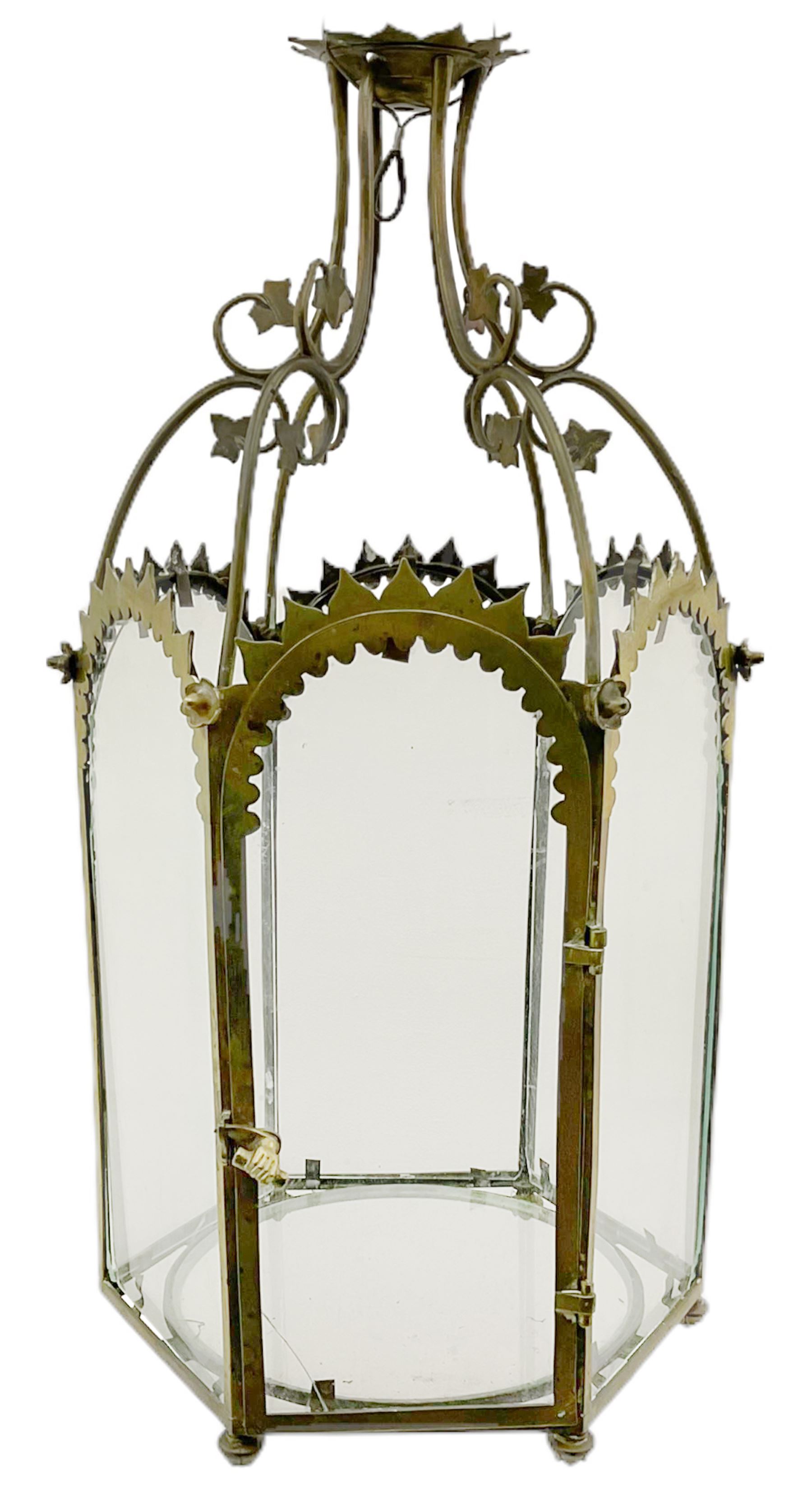 19th century brass and clear glass hexagonal hall lantern, with scrolling wire work open domed top over six arched panels, including a hinged door, the base enclosed with a circular glass panel on turned feet, H64cm