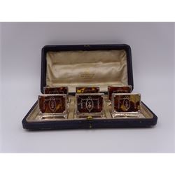 Set of six early 20th century silver mounted tortoiseshell place card holders by Asprey, the rectangular silver reed and ribbon frame bordering a central tortoiseshell panel inlaid with a silver floral motif, upon an oblong foot, hallmarked Asprey & Co Ltd, London 1913, H3cm, contained within a tooled leather fitted case with velvet and silk lined interior 