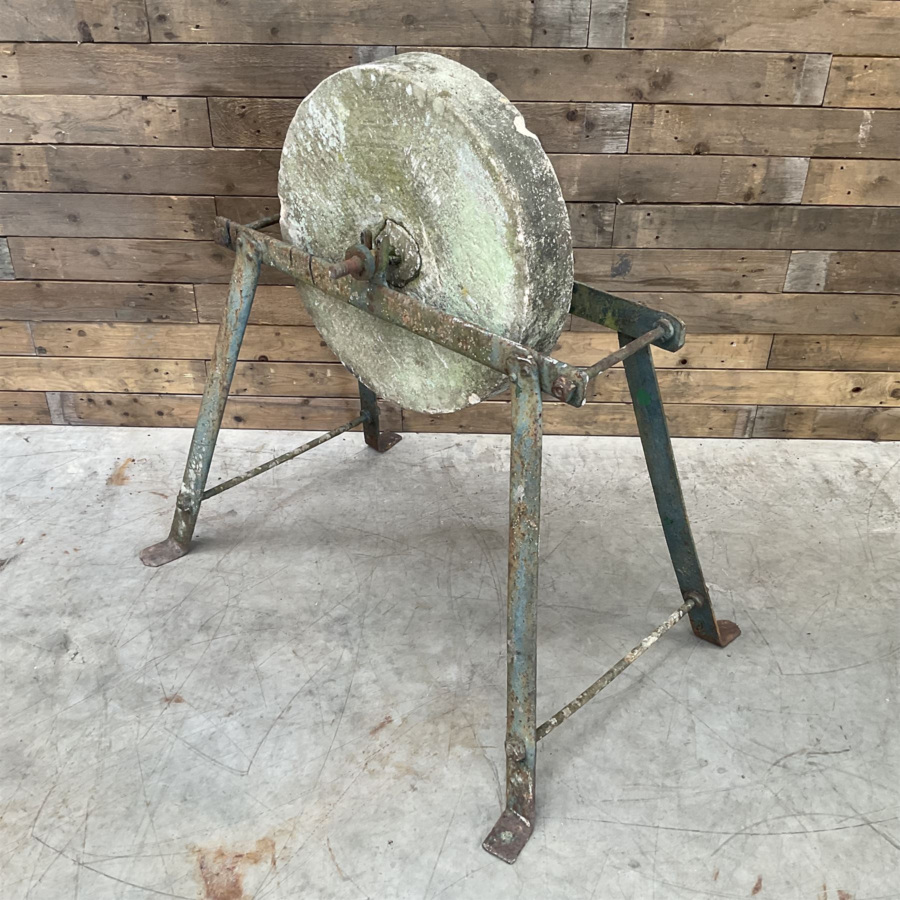 Vintage grindstone sharpening wheel mounted on metal stand, and a cast iron water pump