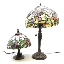 Two Tiffany style table lamps, with leaded glass shades and bronzed bases, largest example overall H49cm, smaller example H26cm.