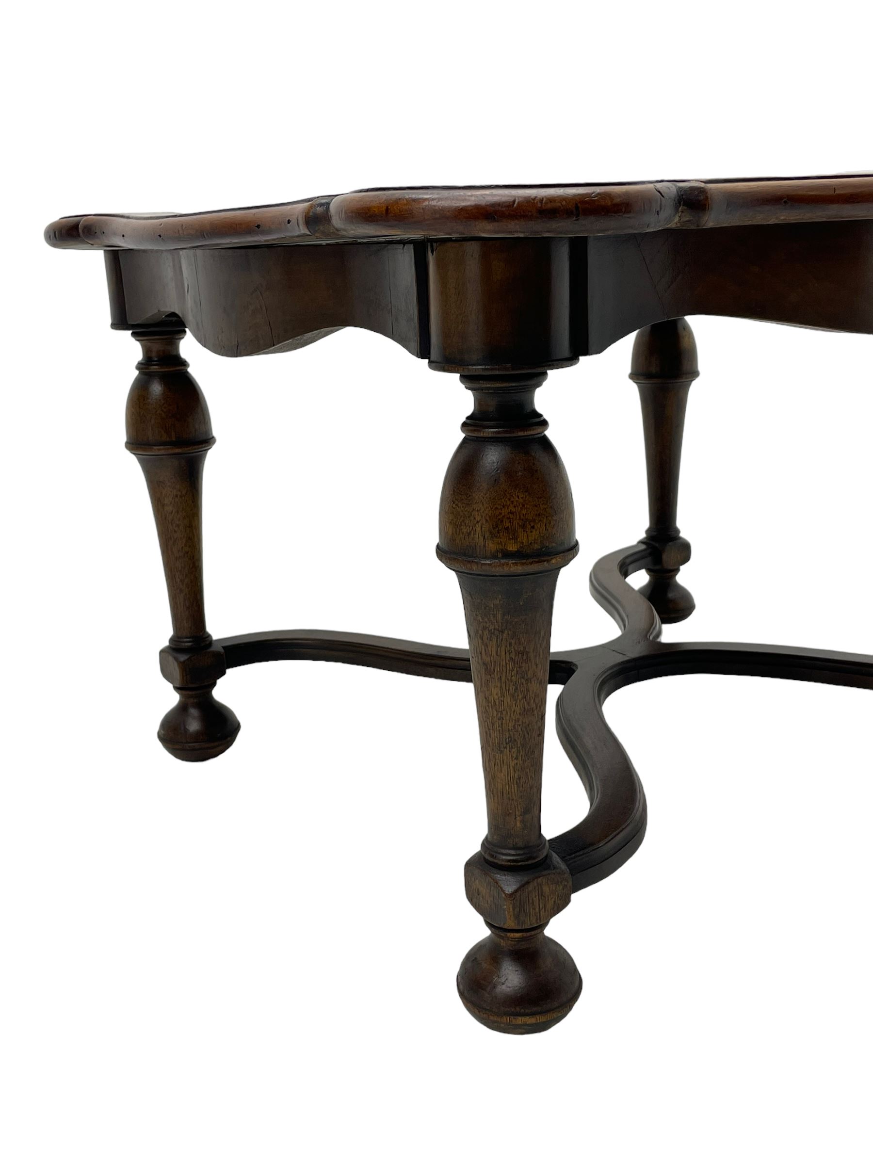 Figured mahogany coffee table, shaped moulded top with oval book-matched veneered panels, on turned supports united by waved X-shaped stretchers 