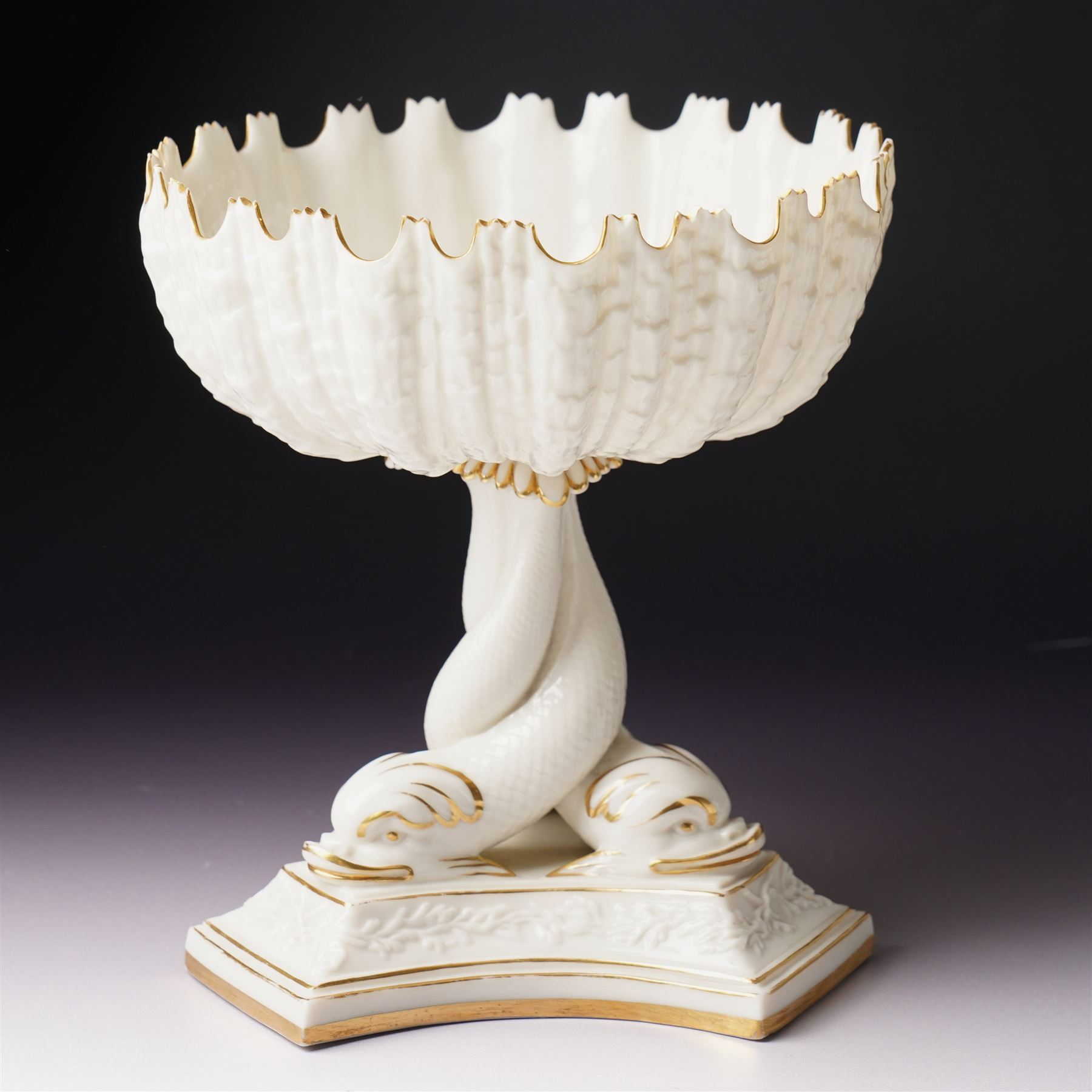 19th century Royal Worcester comport, painted with gilt on a cream ground, the stem formed as three entwined dolphins raising the shell shaped bowl, faint mark to base, H19.5cm