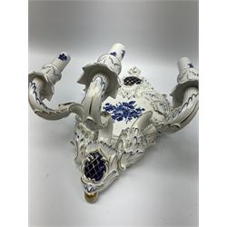 A pair of German Echt Kobalt blue and white wall sconces, the shaped plaques decorated with central floral spray in blue, supporting three scrolling branches, heightened throughout in gilt, H43cm. 