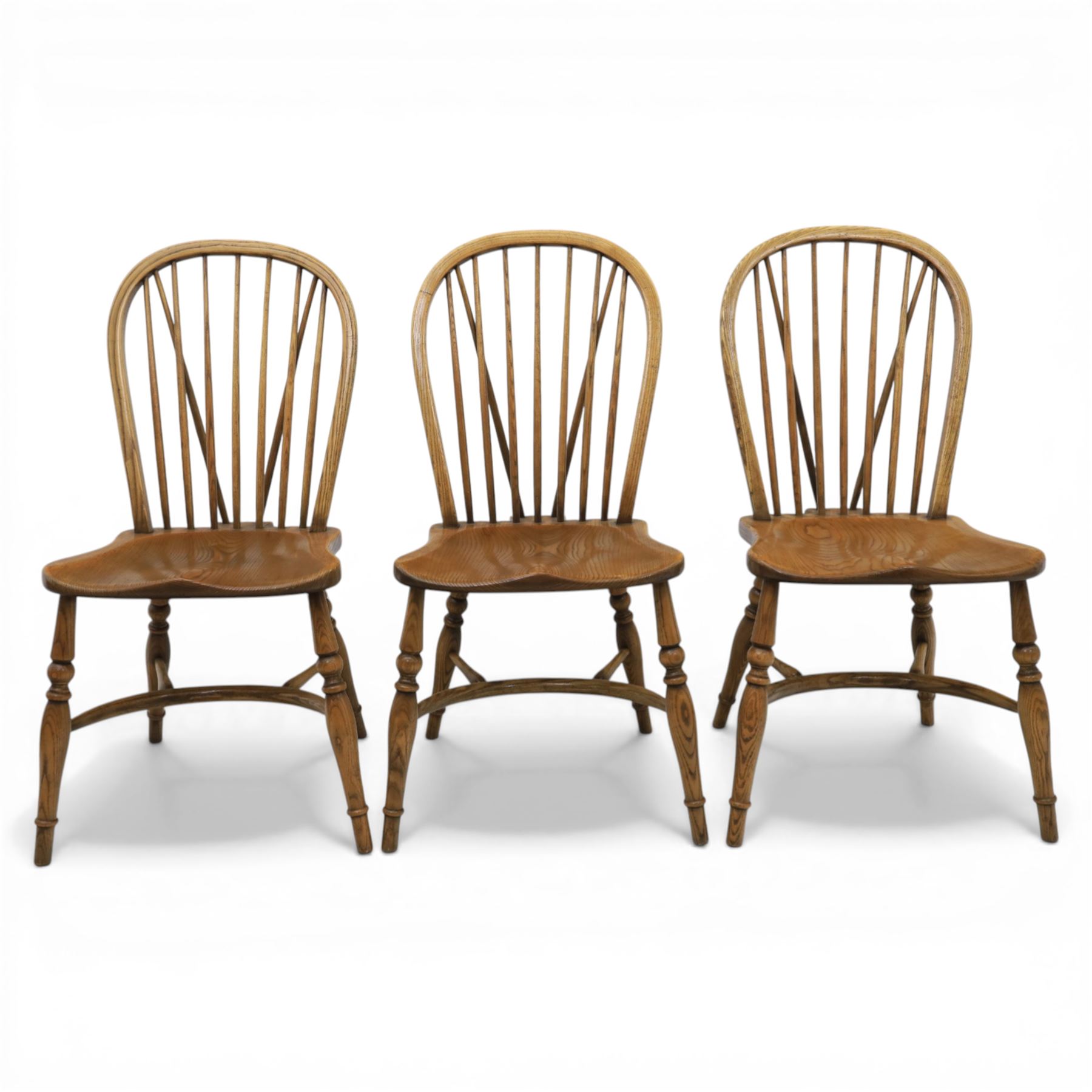 Traditional elm and beech Windsor dining chairs, each with hoop back and turned spindles over a shaped solid seat fitted with loose floral upholstered cushions, raised on turned tapering supports united by crinoline stretchers
