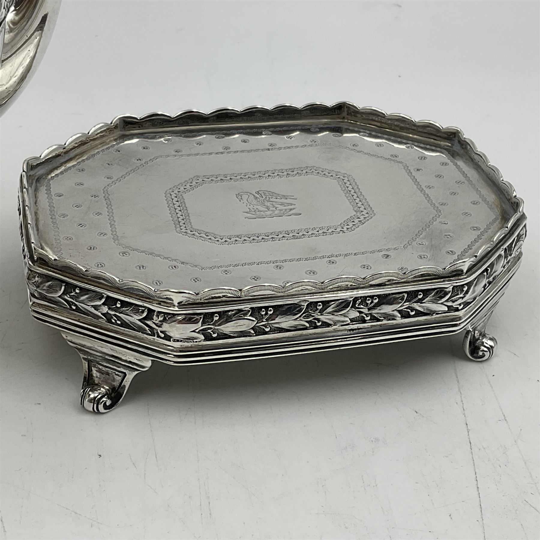 Victorian silver four piece tea service, comprising teapot, teapot stand, twin handled open sucrier and milk jug, each of octagonal form with foliate bud border and engraved decoration including crest to canted panels, and vacant panels, the teapot with ivory finial to the hinged cover and later wooden handle, hallmarked Edward Barnard & Sons Ltd, London1896, teapot including finial H15cm, milk jug including handle H16cm, teapot stand W11.5cm

This item has been registered for sale under Section 10 of the APHA Ivory Act