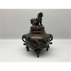 Japanese bronzed koro, the body of globular form with twin cast zoomorphic mask handles, decorated in relief with birds upon blossoming branches, against a ground incised with rushes and peonies, the flat toped domed cover with pierced band and surmounted by a cast figure of a Foo dog, the whole upon three zoomorphic mask feet, with impressed character type mark beneath, H35.5cm
