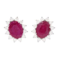 Pair of 18ct white gold ruby and diamond earrings, each stud set with a single oval cut ruby, surrounded by twelve round brilliant cut diamonds, stamped, total ruby weight approx 3.10 carat, total diamond weight approx 0.50 carat