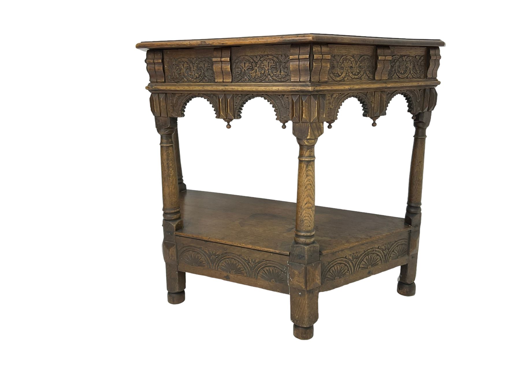 Jacobean design carved oak side or credence table, demi-heptagon top with moulded edge, frieze carved with foliate C-scroll design above ornate arcade carved apron, under-tier united by ring turned pilisters, lower frieze carved with repeating lunettes