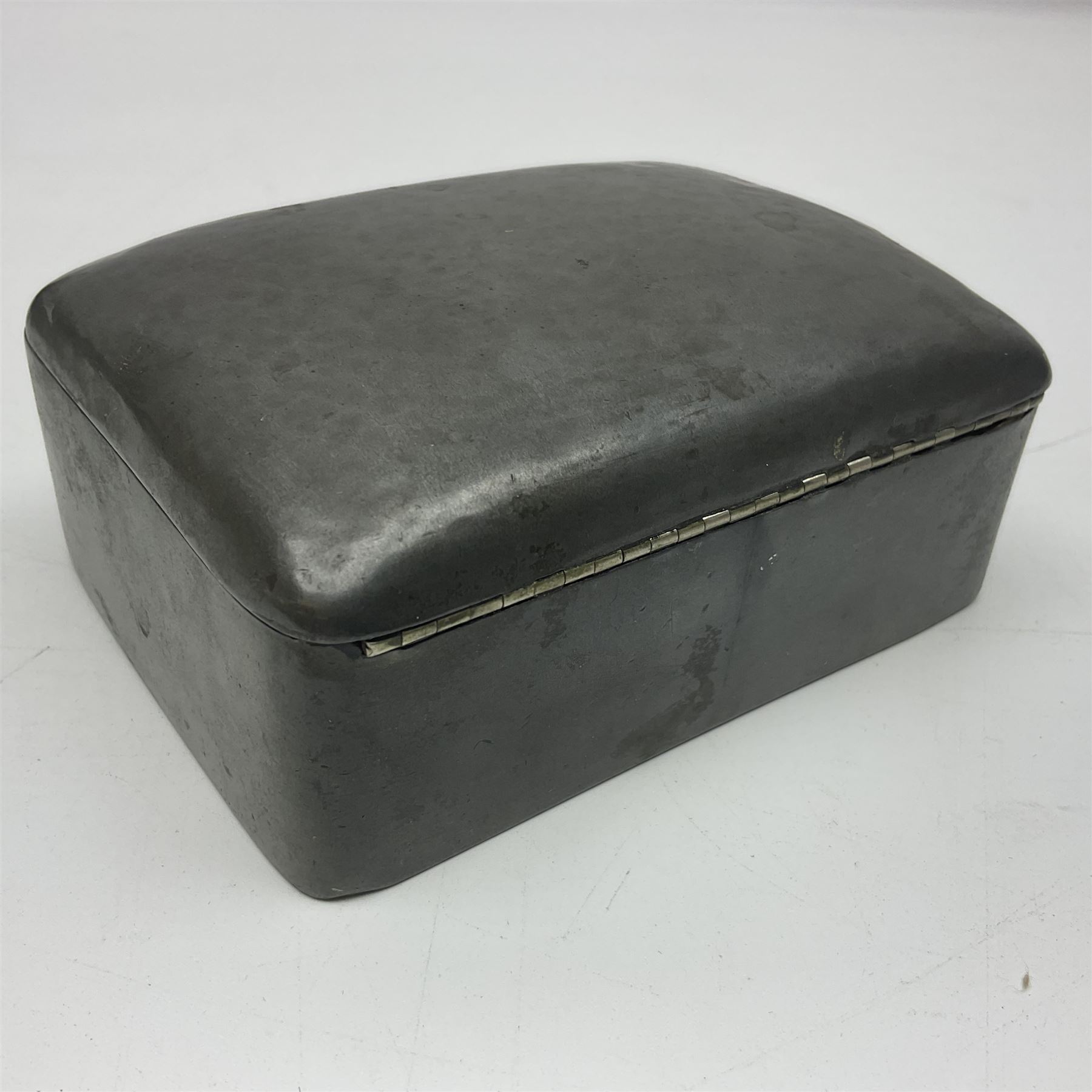 Liberty & Co Tudric pewter cigarette box, of plain rectangular form, with planished decoration to the slightly domed cover, opening to reveal a softwood interior, stamped Made in England 01234 Tudric Solkets beneath, together with another cigarette box, with applied pewter panels repousse decorated throughout with flower heads and leaves, with compartmentalised softwood interior, largest H5.5cm, W23cm