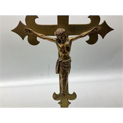 Brass crucifix depicting Christ on the cross, the arms terminating with fleur-de-lis, raised upon circular base, H41cm
