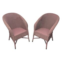 Pair of Lloyd Loom design tub chairs, each with woven wicker construction, curved backrests and painted in a soft pink finish, on cylindrical supports with X-stretchers