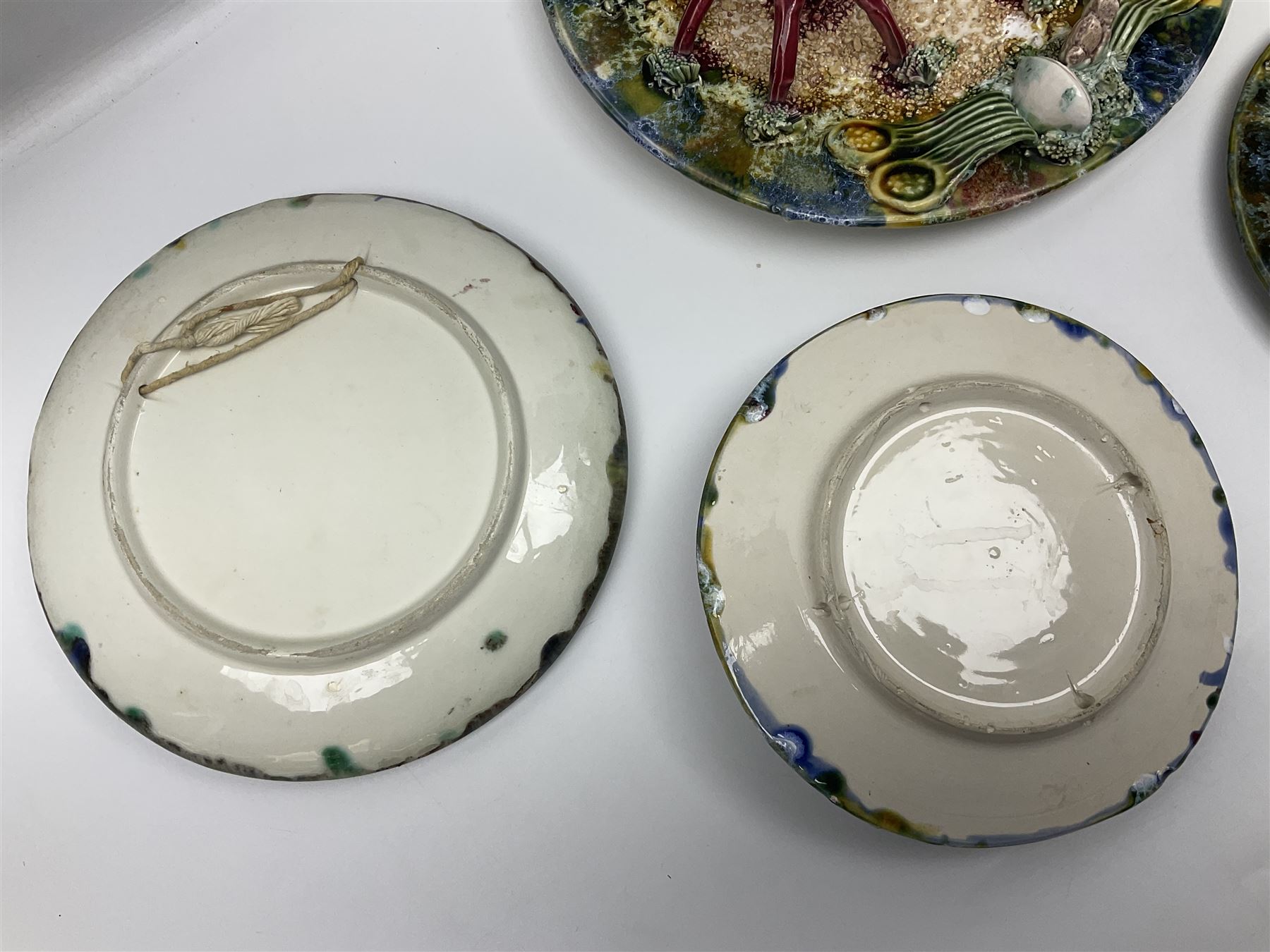 Five 20th Century Portuguese Palissy style Majolica wall plates, all depicting crustaceans to the centre modelled in relief surrounded by encrustations and shells, both with impress marks beneath, largest D29cm