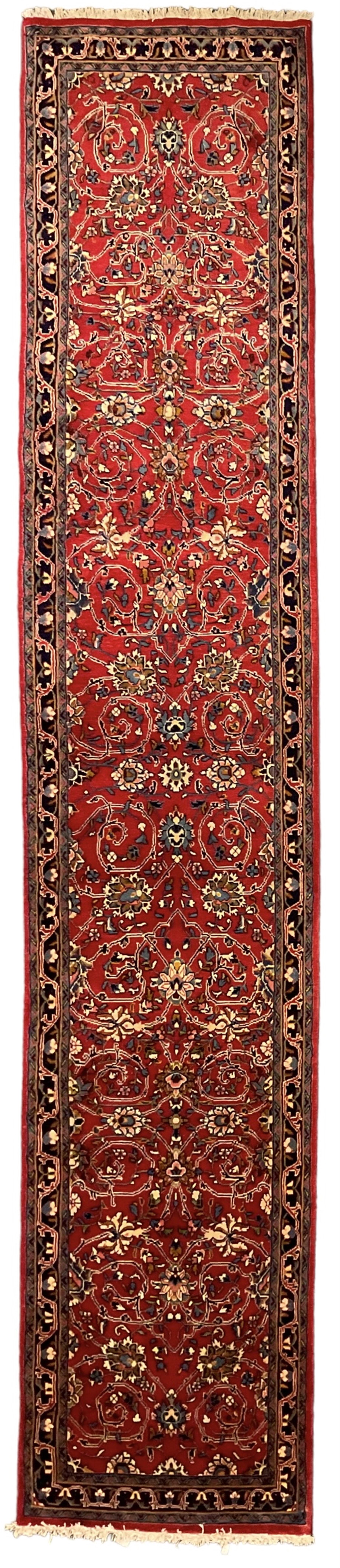Central Persian Kashan crimson ground runner rug, the field decorated with interlacing branch and stylised flower head motifs, the guarded indigo border with repeating trailing foliate patterns