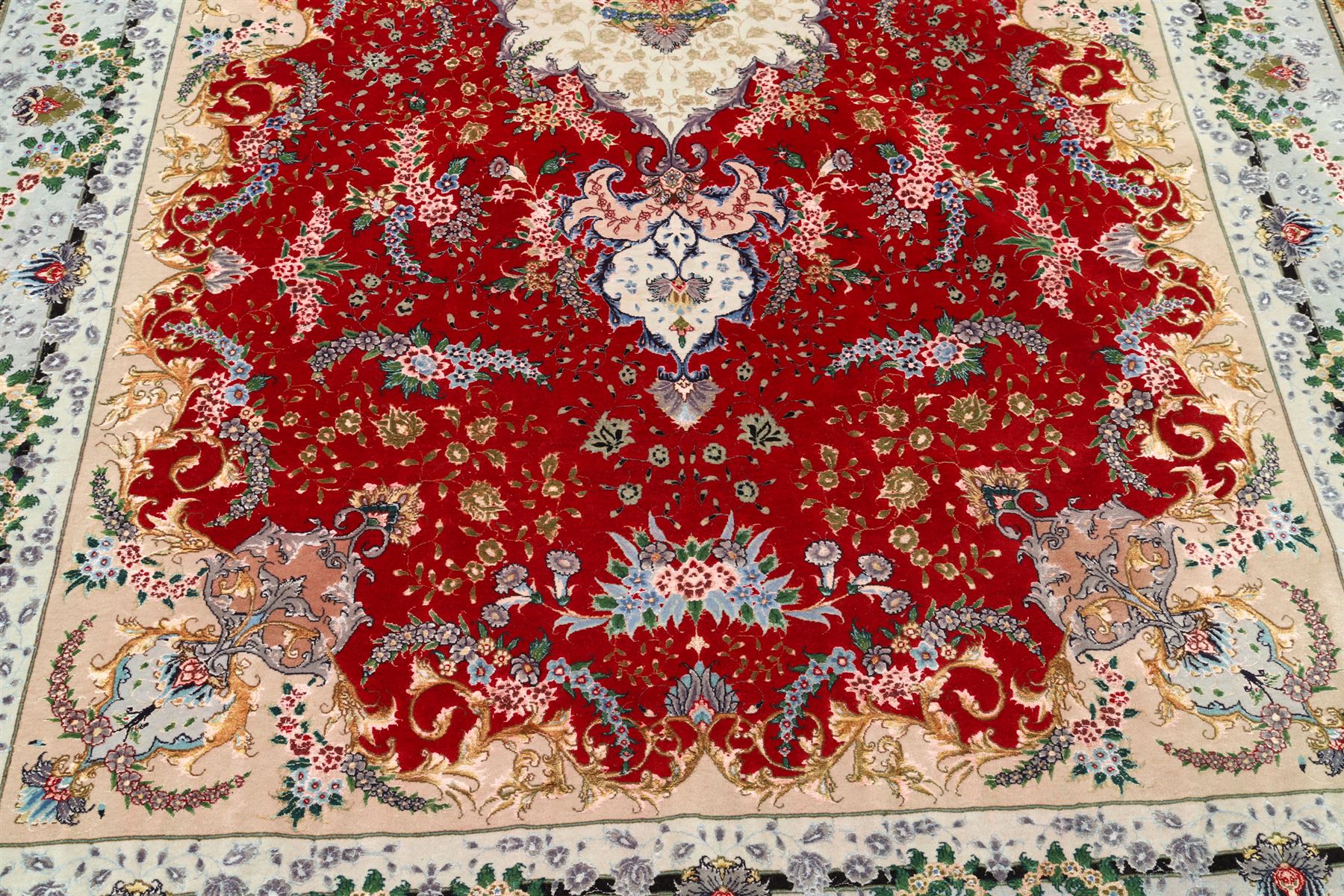 Fine Persian silk inlaid crimson ground Tabriz rug, the shaped field decorated with a central foliate pole medallion filled and surrounded by finely knotted floral motifs and trailing foliage, the cyan guard stripe with bold festoons and palmette motifs