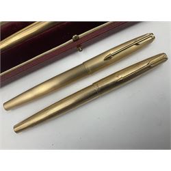 Three rolled gold Parker fountain pens, comprising an example with a gold nib marked 14K 585 and barrel with a shell stamp, a Parker 61 fountain pen with inset gold arrow to the nib, and another similar, all with striated decoration and arrow clips to the caps, L13cm, one with box