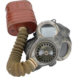 Two gas masks, together with a green tin helmet, cased within a wooden box with hinged lid 