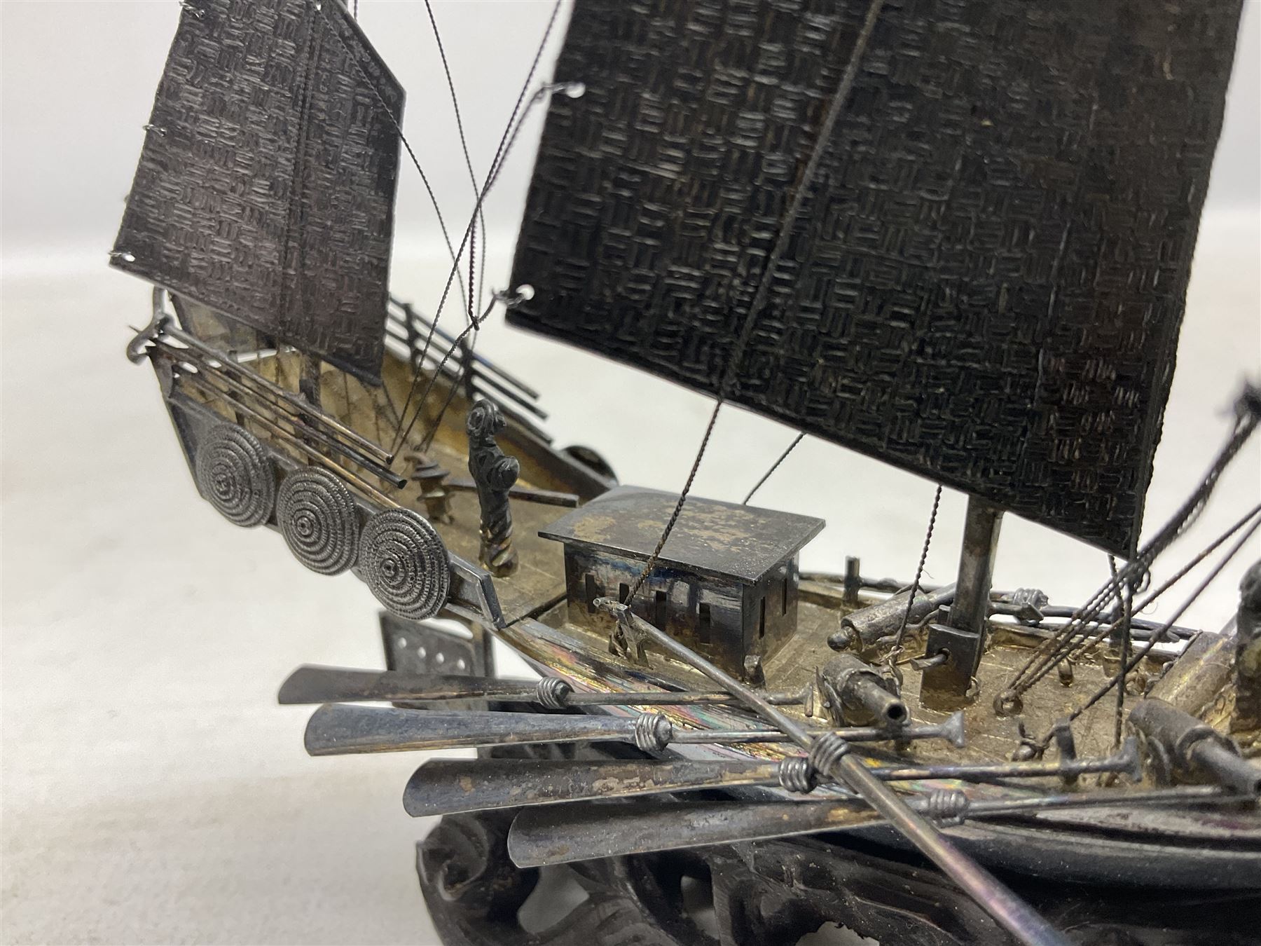 Chinese miniature silver model of a junk ship, with textured sails, mounted upon a carved wooden stand, H14cm