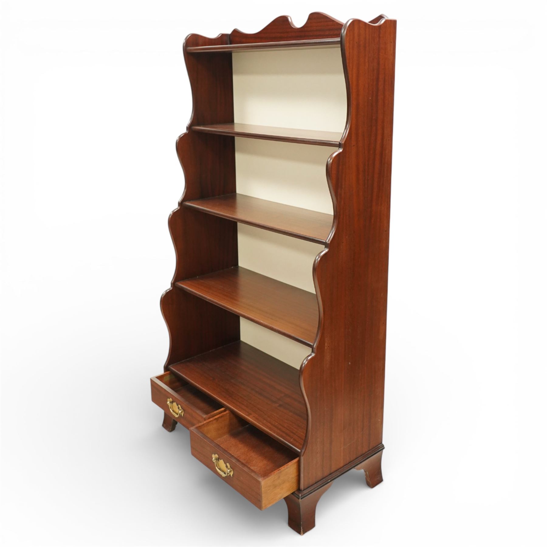 Early 20th century mahogany waterfall bookcase, shaped and serpentine side uprights with scalloped cresting, fitted with four open shelves above two short drawers with brass drop handles, raised on shaped bracket feet
