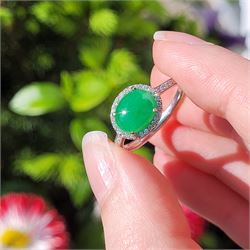 Platinum jadeite and diamond cluster ring, single oval cabochon cut jadeite of 2.20 carat, surrounded by round brilliant cut diamonds and diamond set shoulders, stamped Plat