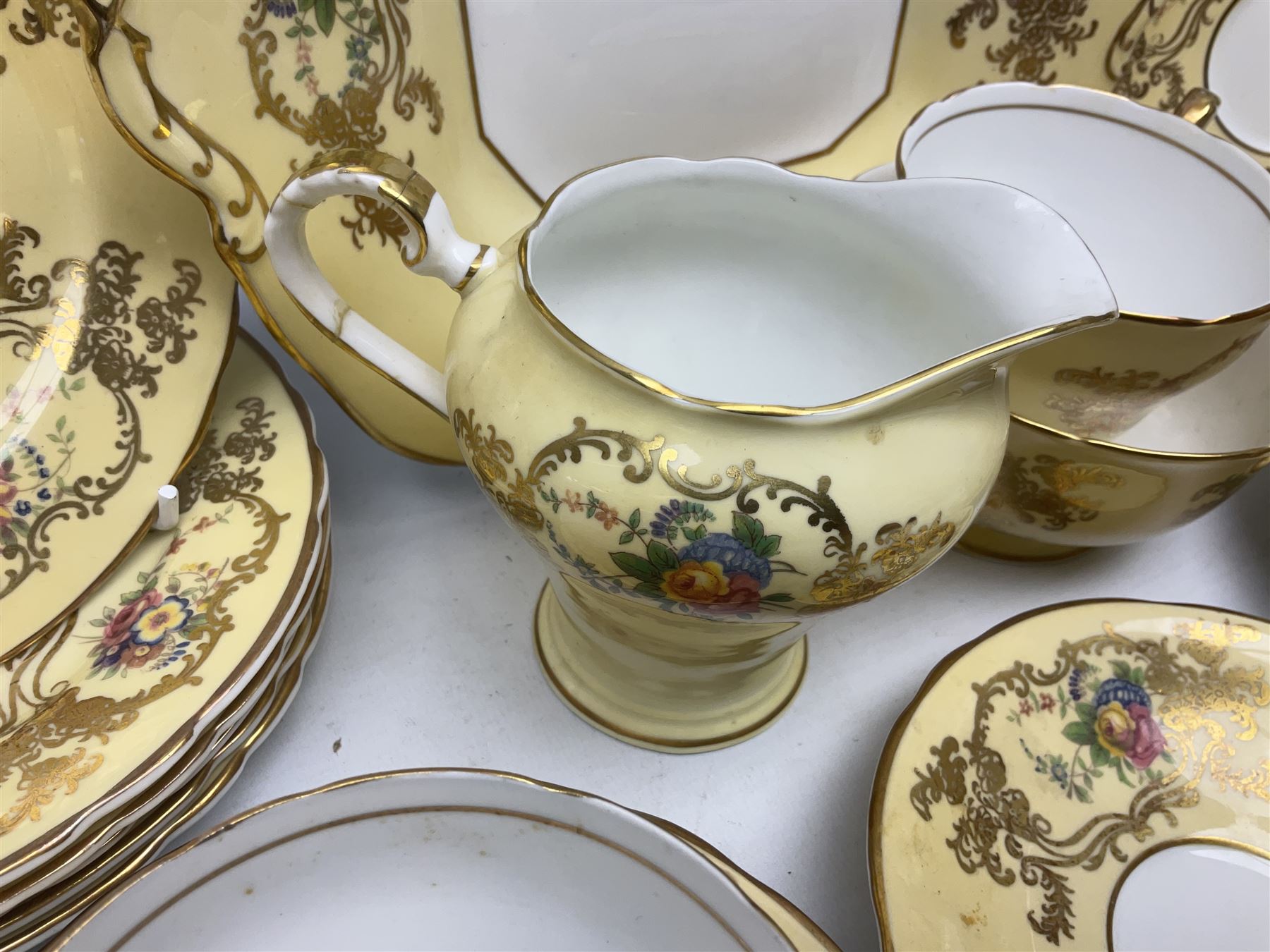 Aynsley tea service for six, decorated with floral sprays in ornate gilt detailing on cream ground, comprising six teacups and saucers, open sucrier and milk jug and cake plate, all with printed marks beneath