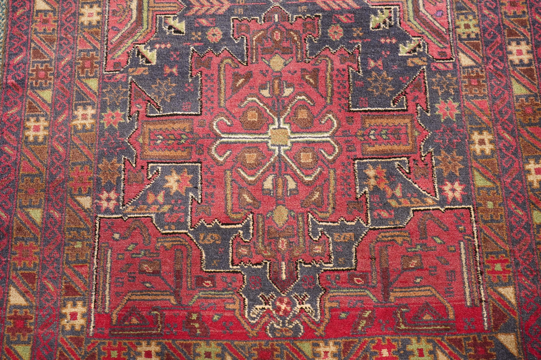 Four small Persian and Caucasian design rugs, comprising a Kazak rug with twin hooked medallions on a red ground, Baluchi rug with geometric motifs on a muted red ground, Shiraz rug with a central ivory and red medallion on a blue ground, and a Bokhara mat with four guls on a rose ground, each enclosed by geometric borders, largest 143cm x 88cm (4)