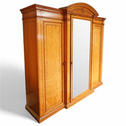 Victorian neoclassical style satinwood triple-section wardrobe, the central mirror section and arched pediment with carved monogram flanked by two panelled crossbanded doors, revealing two drawers and grooves for shelves, the hanging cupboards each with a single drawer, the whole supported on a plinth base