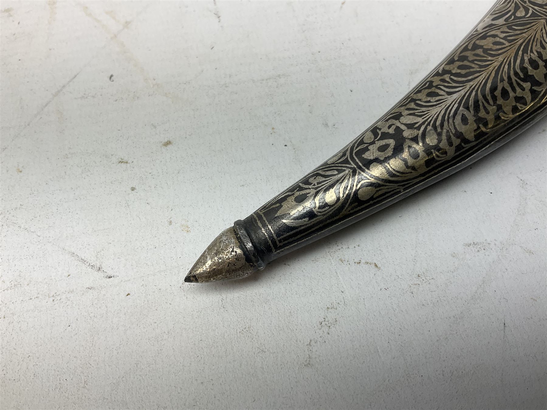 Indian Khanjar dagger with 28cm curving damascus steel blade inlaid with silver floral emblem, white metal and niello style grip in the form of a bird's head with pronounced beak and matching scabbard L44cm overall