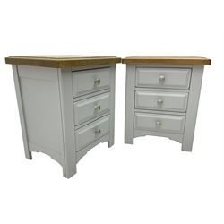 Pair of painted bedside chests with oak top, fitted with three drawers, raised on square supports with shaped apron, in cream finish