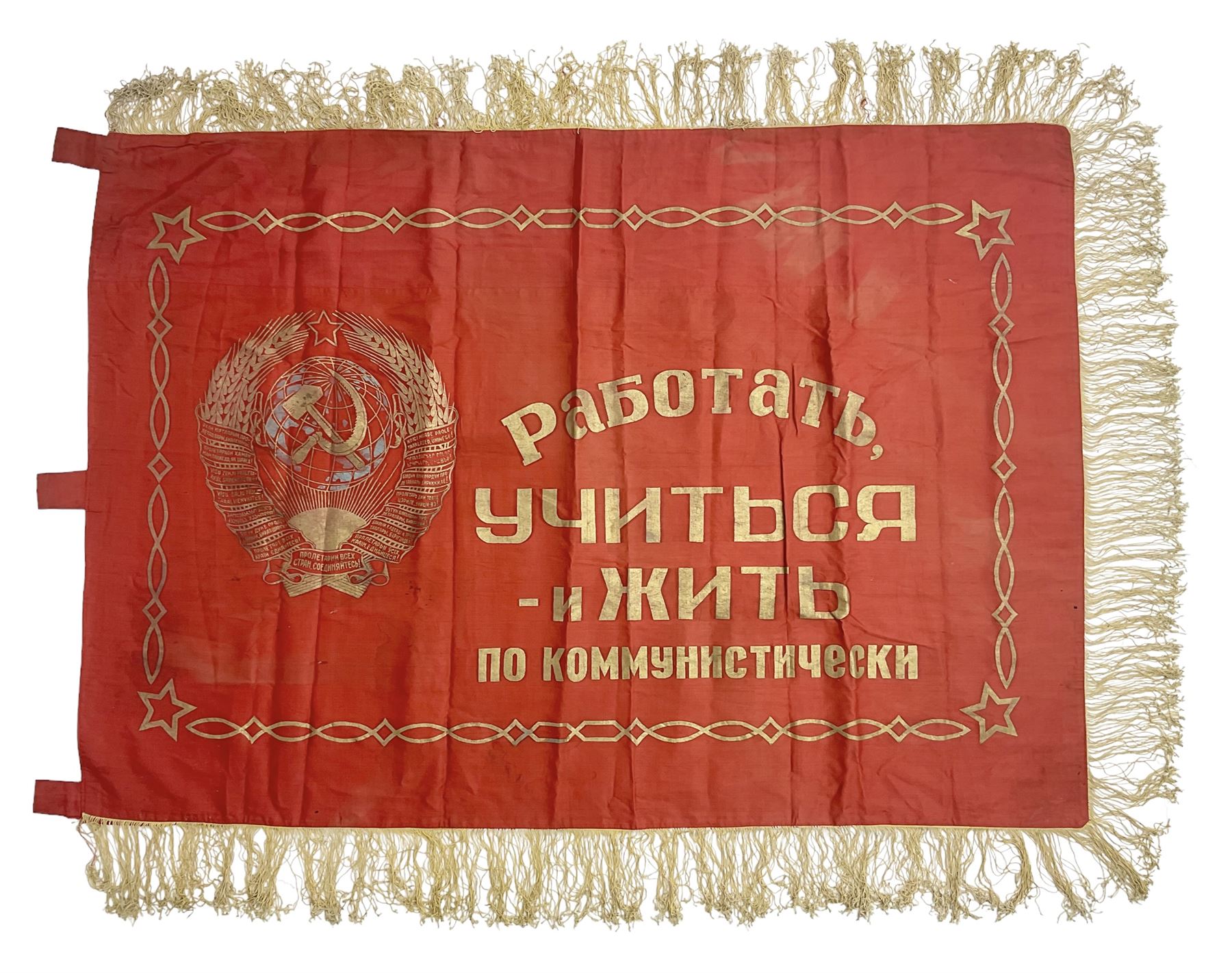 1970s Soviet banner printed in gold on a red ground, roughly translates as 'Transferable Banner - To the winner in the Socialist Competition' and 'Work Study Live by Communism' verso; wreath of wheat ears to either side; tassels on three sides 110 x 155cm
