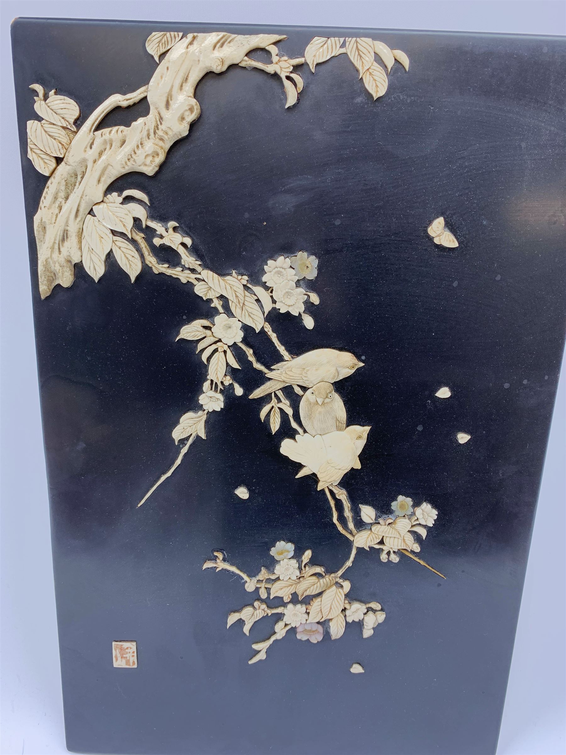 An early 20th century Japanese Shibayama panel, depicting three birds seated upon a blossoming branch in ivory and mother of pearl, with applied ivory character mark panel lower left, H45.5cm L30cm. 